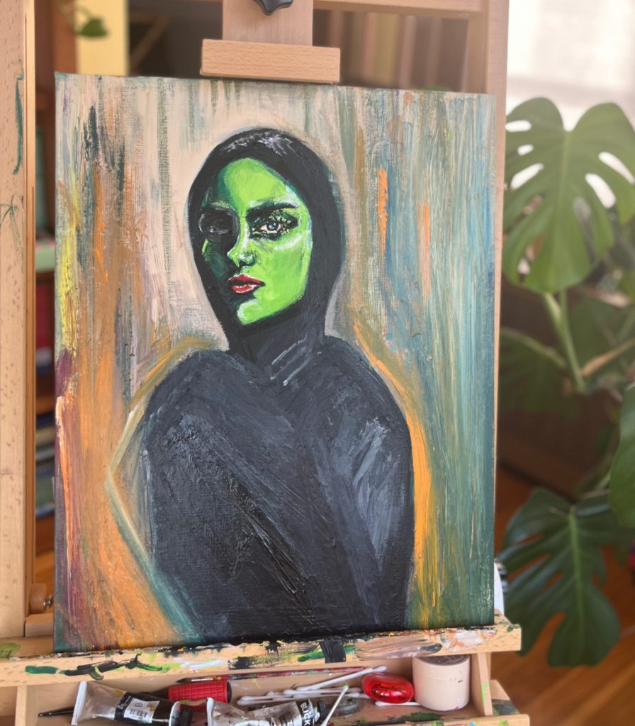 Portrait of a green woman with a defiant expression wearing a chador-like garb.